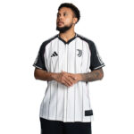 Man wearing a white Juventus football jersey with black vertical pinstripes, Adidas logo, and Juventus crest, arms folded in front of him.