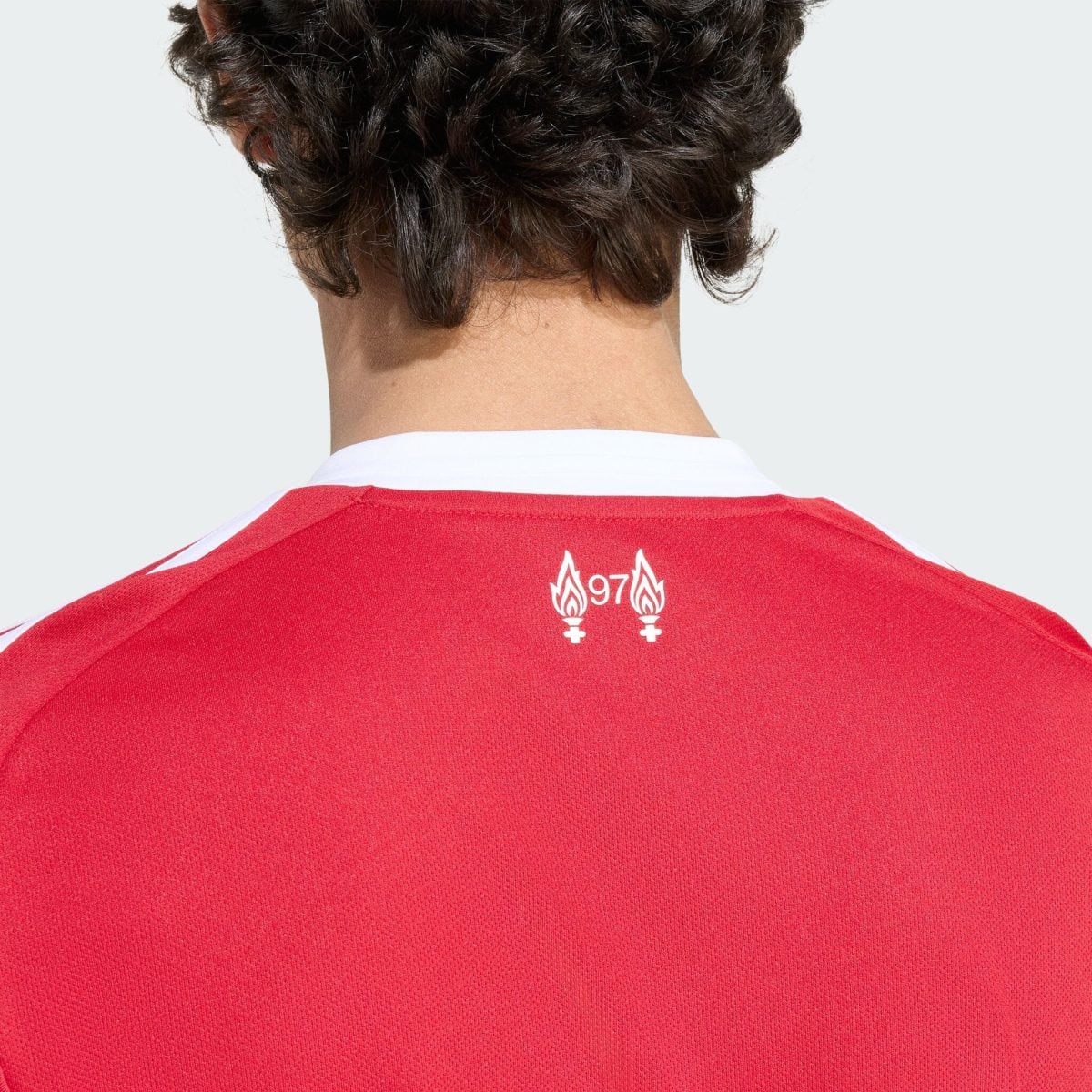 Back view of a person in a red sports jersey with white trim; short dark hair at the nape.