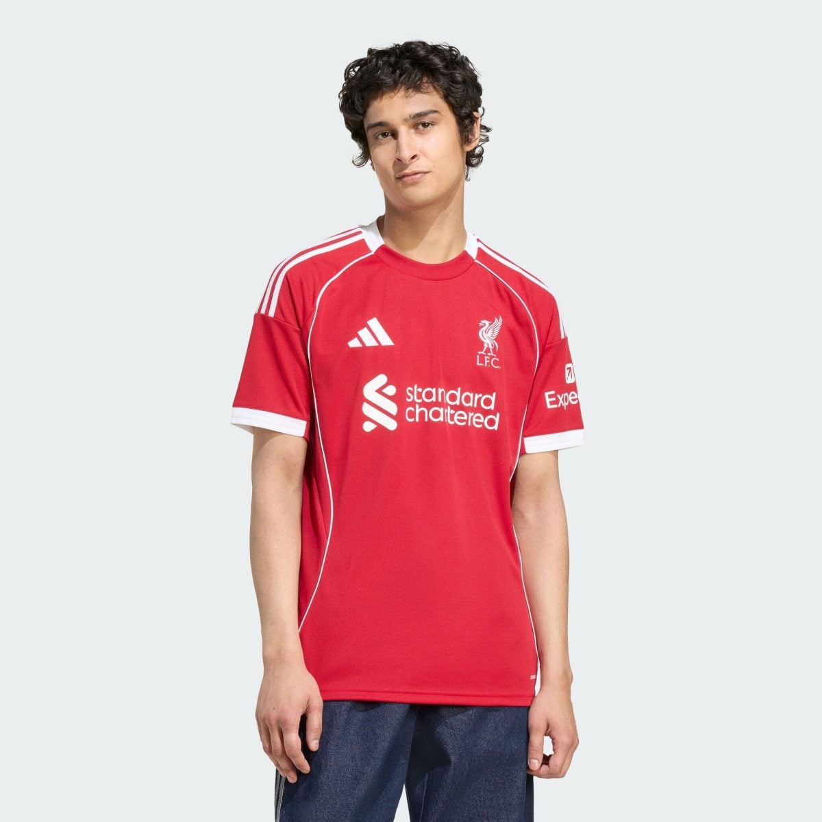 Young man wearing a red Liverpool FC jersey against a light gray background.
