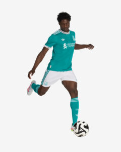 JV6427_5_APPAREL_OnModel_WalkingView_custom_1-lowres | UAE SPORT STORE Soccer player in teal away kit with white shorts kicking a soccer ball.