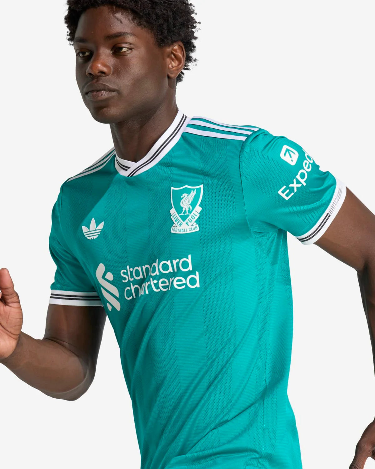 JV6427_8_APPAREL_OnModel_DetailView2_custom_1-lowres | UAE SPORT STORE Athlete wearing a teal Liverpool FC football jersey with the Standard Chartered sponsor and crest visible on the chest.