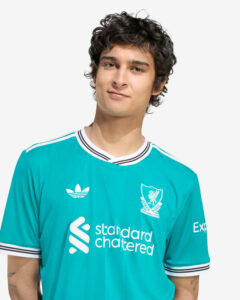 Portrait of a young man in a teal football jersey with white stripes, smiling slightly on a white background.