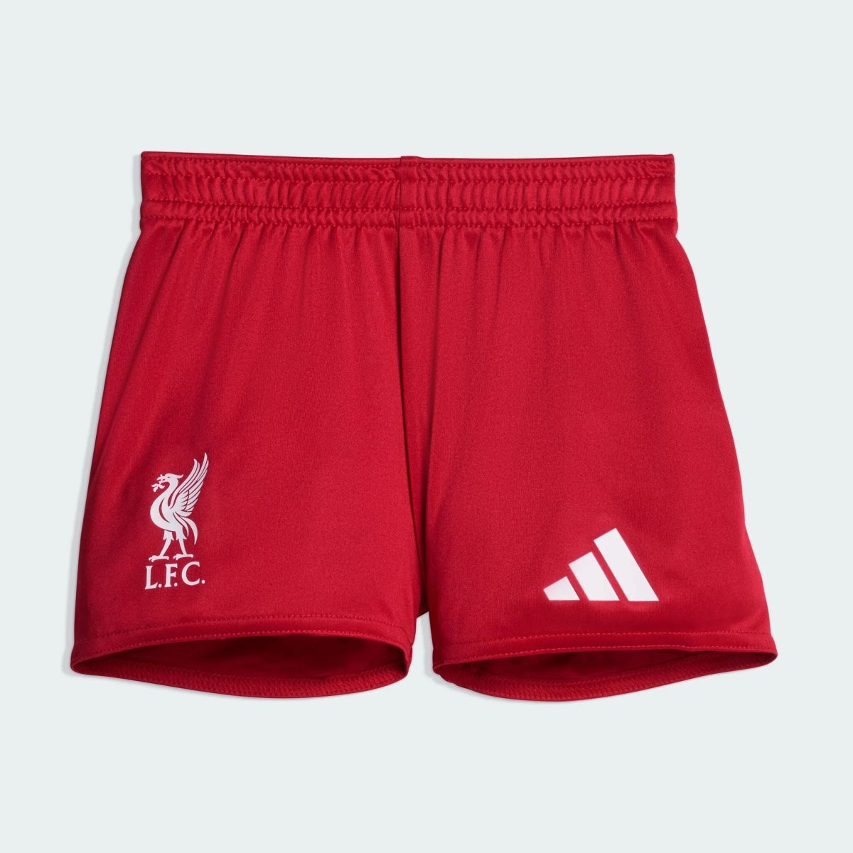 Close-up of red athletic shorts showing a white Liverpool FC crest on the left leg and white Adidas stripes on the right leg.