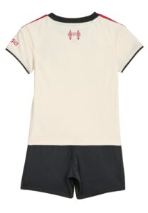Back view of a cream polo shirt with black collar trim, red shoulder stripes, and a small red emblem near the neck, paired with black shorts.