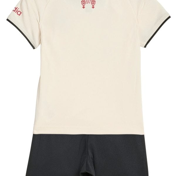Back view of a cream polo shirt with black collar trim, red shoulder stripes, and a small red emblem near the neck, paired with black shorts.