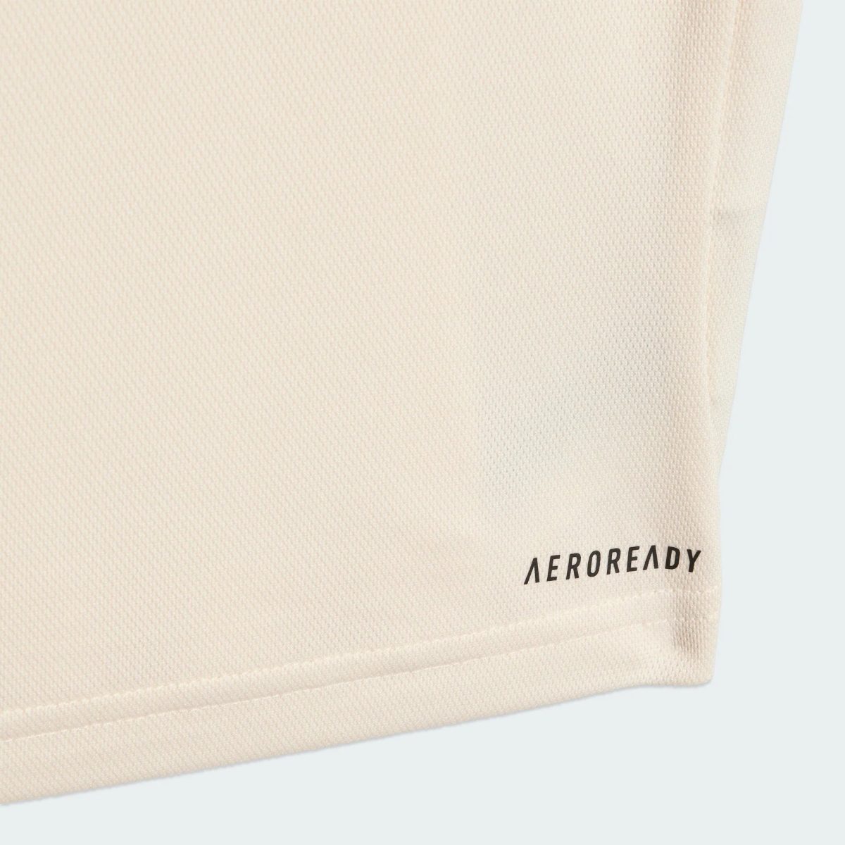 Close-up of beige fabric texture with a small corner of black text reading 'AEROREADY' in the bottom-right.