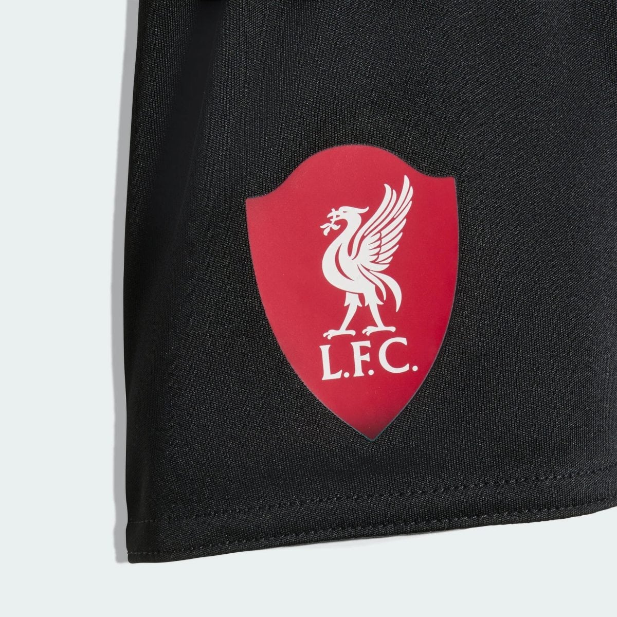 Red Liverpool FC shield badge with white liverbird on dark fabric surface (likely a bag).