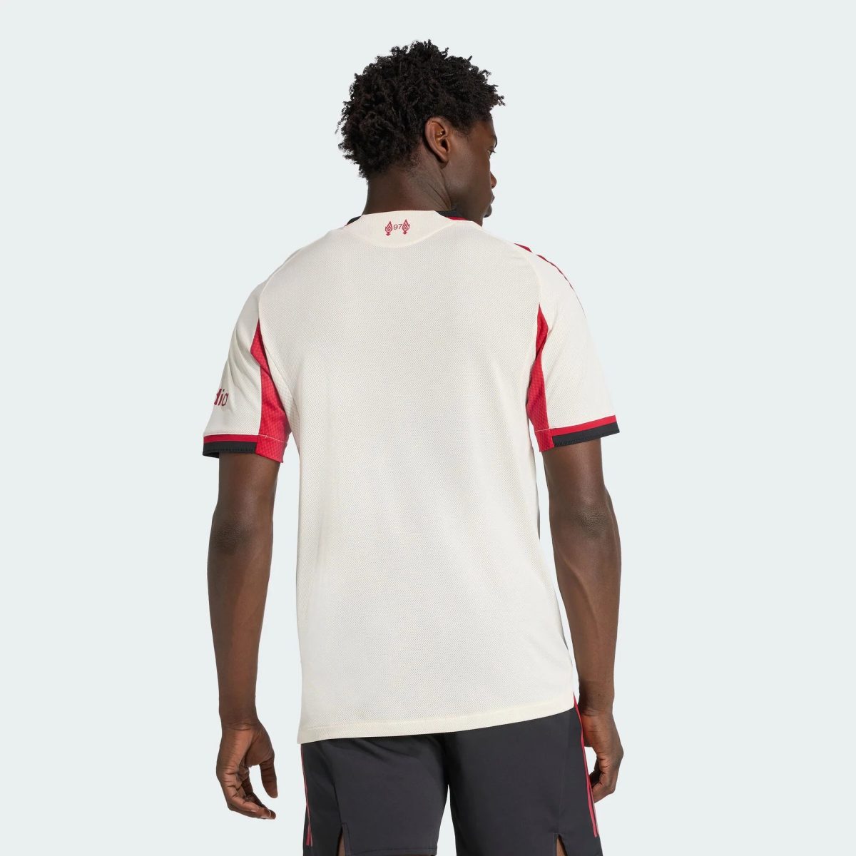Back view of a person wearing a white athletic jersey with red accents, facing away from the camera.