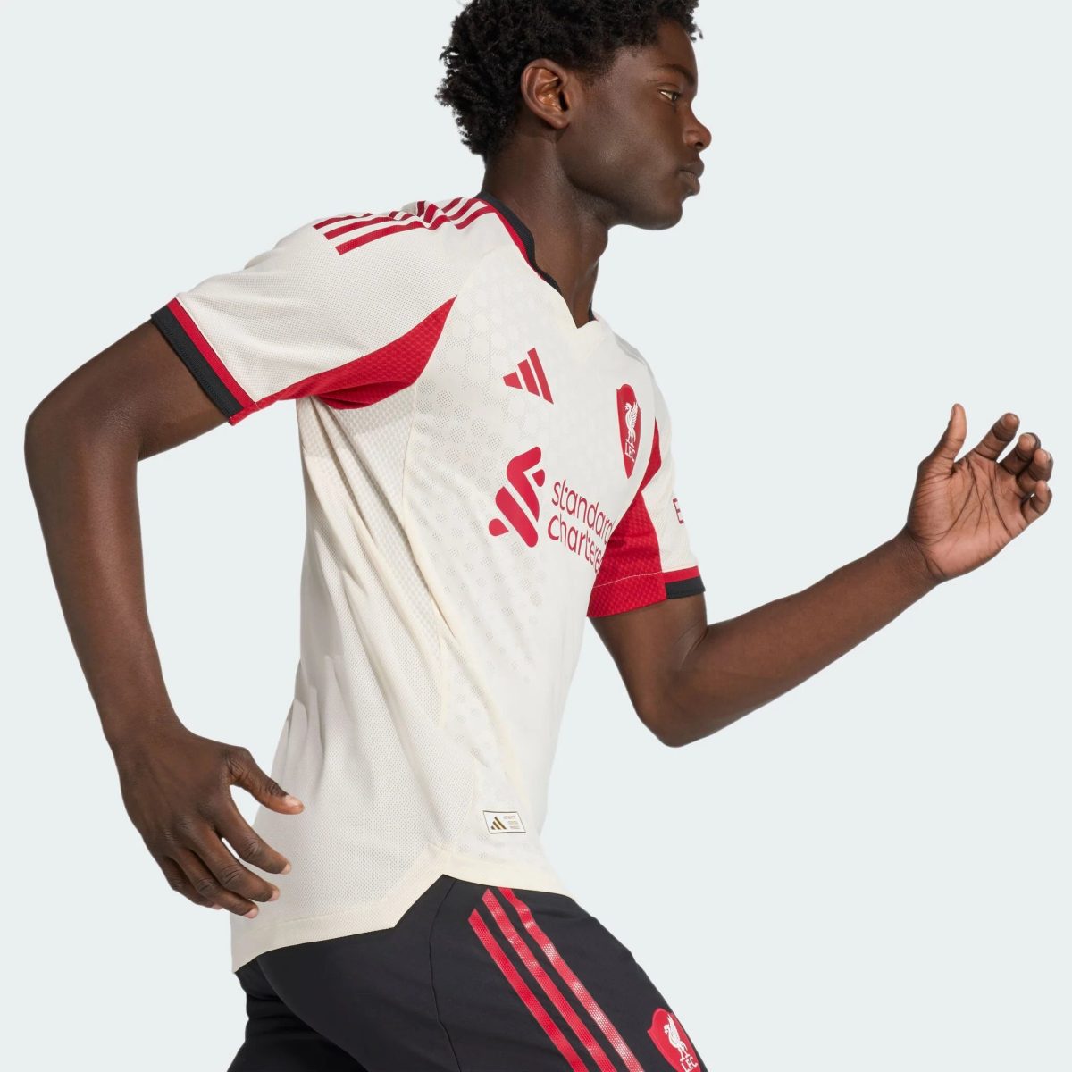 Soccer player in a white jersey with red accents running to the right, shown in profile.