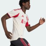 Soccer player in a white jersey with red accents running to the right, shown in profile.