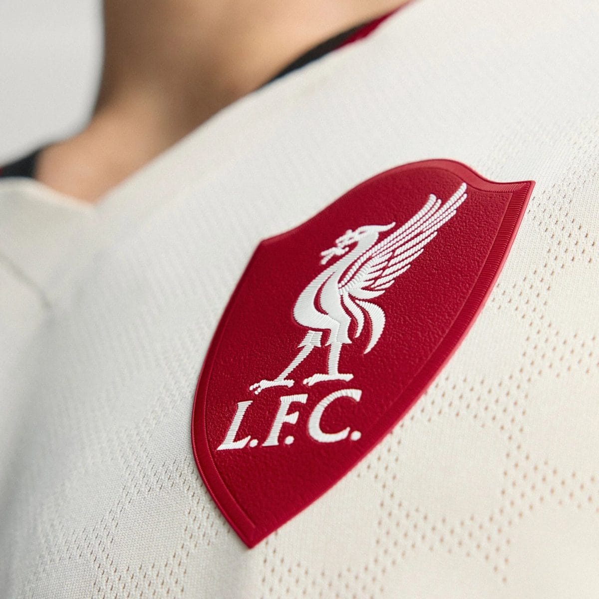Close-up of a red embroidered patch with white cursive lettering on light fabric.