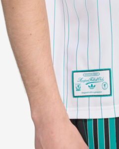 Close-up of a white jersey with turquoise vertical pinstripes and a sewn patch reading Liverpool Football Club.
