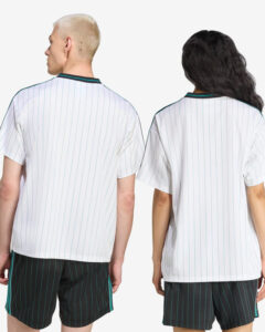 Two models seen from behind wearing matching white pinstripe jerseys with teal trim and dark pinstripe shorts with teal accents.