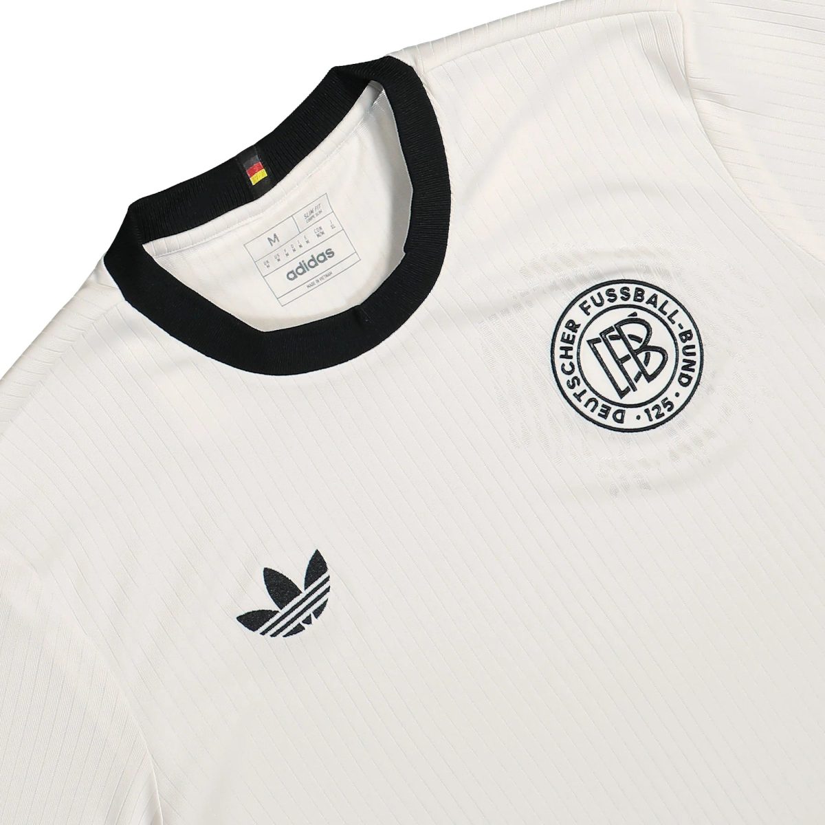 Close-up of a white Adidas jersey with a black collar, subtle pinstripes, and a circular team crest.