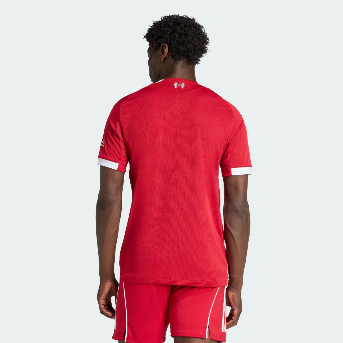 Person wearing a red athletic jersey viewed from the back, displaying a small logo at the neck.