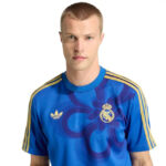 Man wearing a blue Real Madrid football jersey with yellow shoulder stripes, facing the camera.