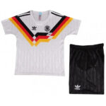 Youth Germany national team soccer kit: white jersey with black, red, and gold chevron and crest, paired with black shorts.