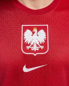 Red sports jersey featuring the Polish national emblem—a white eagle on a red shield—with a white Nike swoosh nearby.