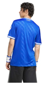 Back view of a man in a blue soccer jersey with white trim, 'RMCF' at the collar.