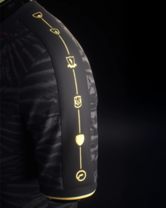LeftSleeve_3000x_68e21199-e929-4fa5-b20a-1e2099af7268 | UAE SPORT STORE Close-up of a dark, patterned sleeve with glowing gold line markers and symbols along the seam, suggesting a futuristic suit.