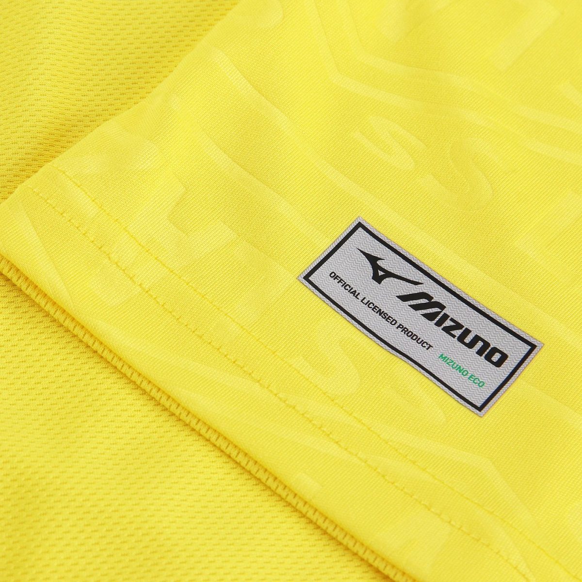 Close-up of bright yellow sports fabric with a Mizuno official licensed product tag.