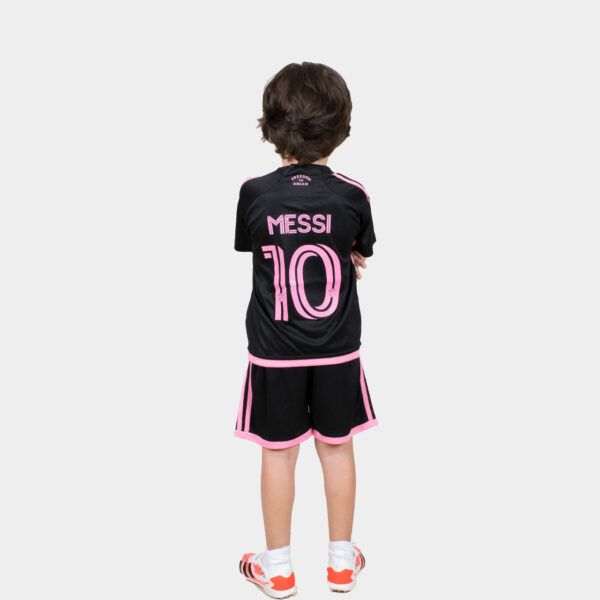 Back view of a child wearing a black football jersey with pink 'MESSI 10' and pink trim, standing with arms crossed.