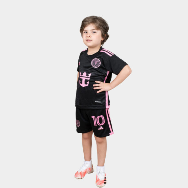 Young boy standing with hands on hips, wearing a black and pink soccer kit with the number 10 on his shorts.