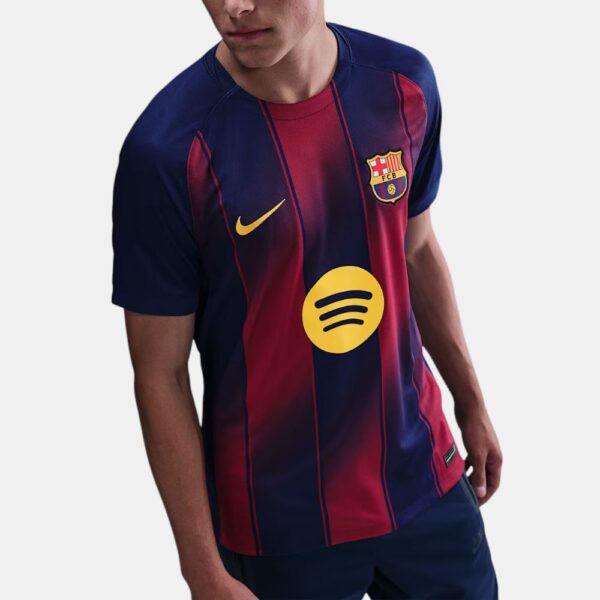 Man wearing a FC Barcelona soccer jersey with a yellow Spotify logo on the chest, navy and red stripes.",