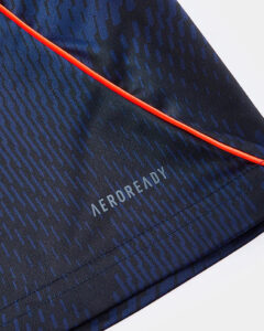 Close-up of navy athletic fabric with a geometric blue pattern and a bright red seam, showing the 'AEROREADY' logo.