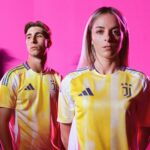 Two young adults in yellow Juventus jerseys stand against a bright pink background, looking off-camera with serious expressions.