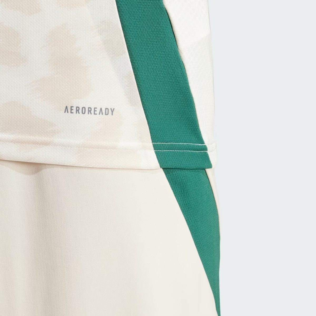 Close-up of beige fabric with a teal strap crossing the image and the 'AEROREADY' logo visible on the material.