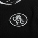 Close-up of a black fabric with a white circular logo featuring a dinosaur skeleton inside the circle.