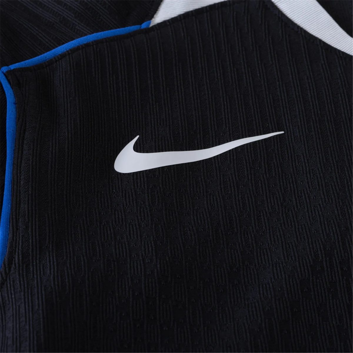Close-up of black textured fabric with a white Nike swoosh logo and blue trim along the seam, suggesting athletic apparel.