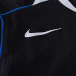 Close-up of black textured fabric with a white Nike swoosh logo and blue trim along the seam, suggesting athletic apparel.