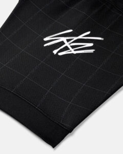 Close-up of black textured fabric with a white scribble-style logo.