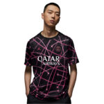Young man wearing a black soccer jersey with pink neon grid patterns and the 'QATAR AIRWAYS' logo on the front.