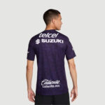Back view of a man wearing a purple patterned sports jersey with telcel, SUZUKI, and Caliente logos.