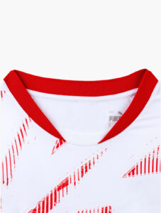 Close-up of a white shirt collar with red ribbed trim and red diagonal graphic pattern, brand visible inside neck.