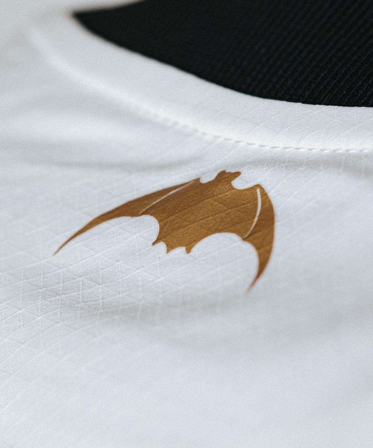 Close-up of white fabric featuring a brown bat logo