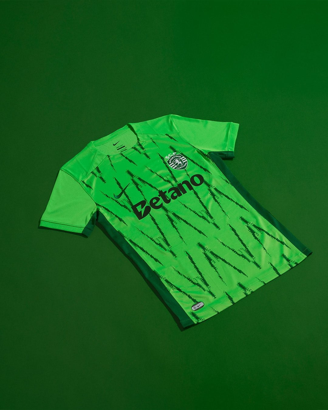 PAfNjkI5RjnRBVk | UAE SPORT STORE Bright green football jersey laid flat with black vertical stripe scratches and the 'Betano' sponsor text across the chest, crest near the collar.