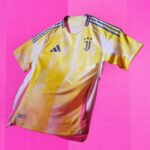 Juventus football jersey in yellow with blue stripes and crest on a bright pink background