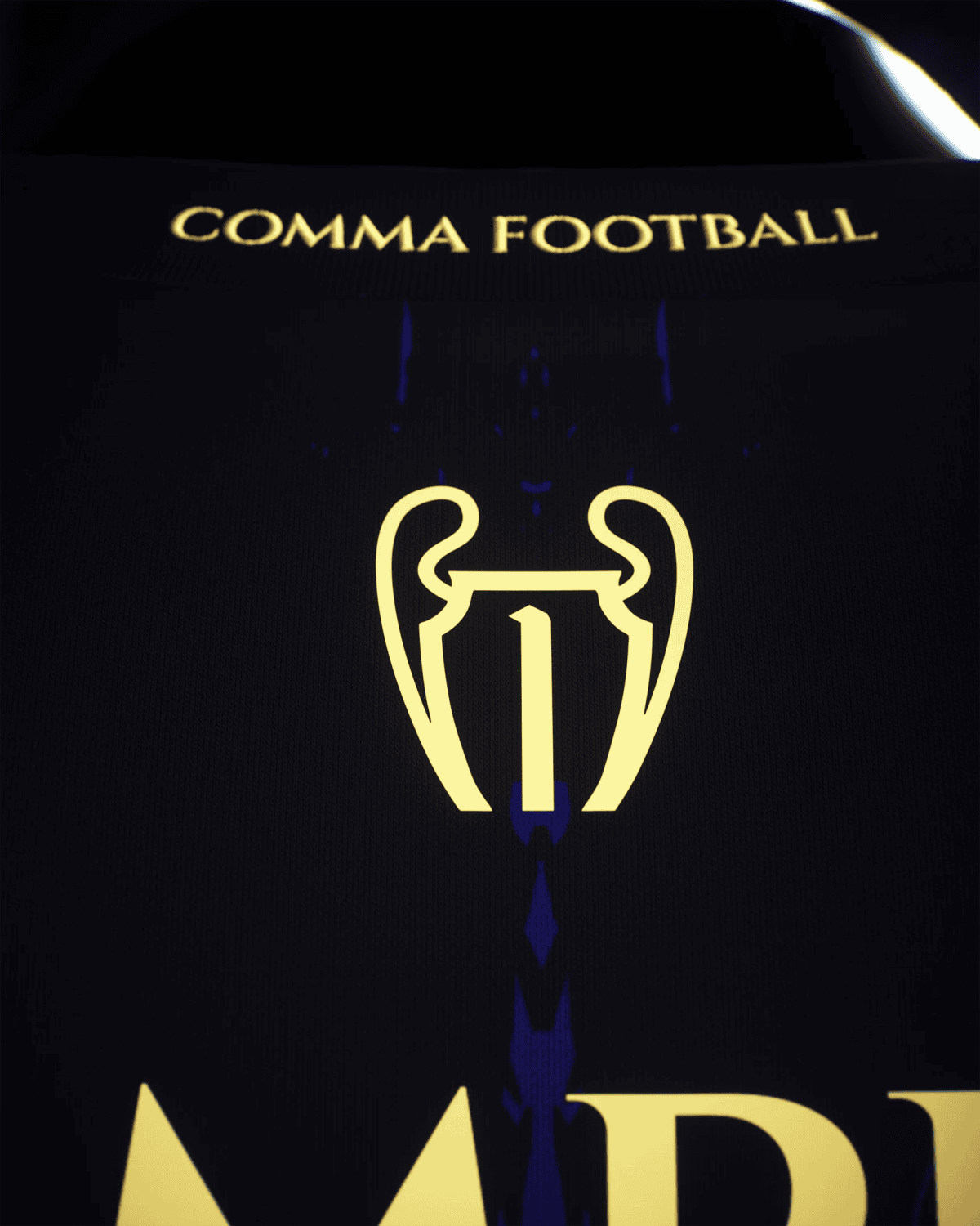 Close-up of a dark surface with gold text 'COMMA FOOTBALL' and a yellow trophy emblem.