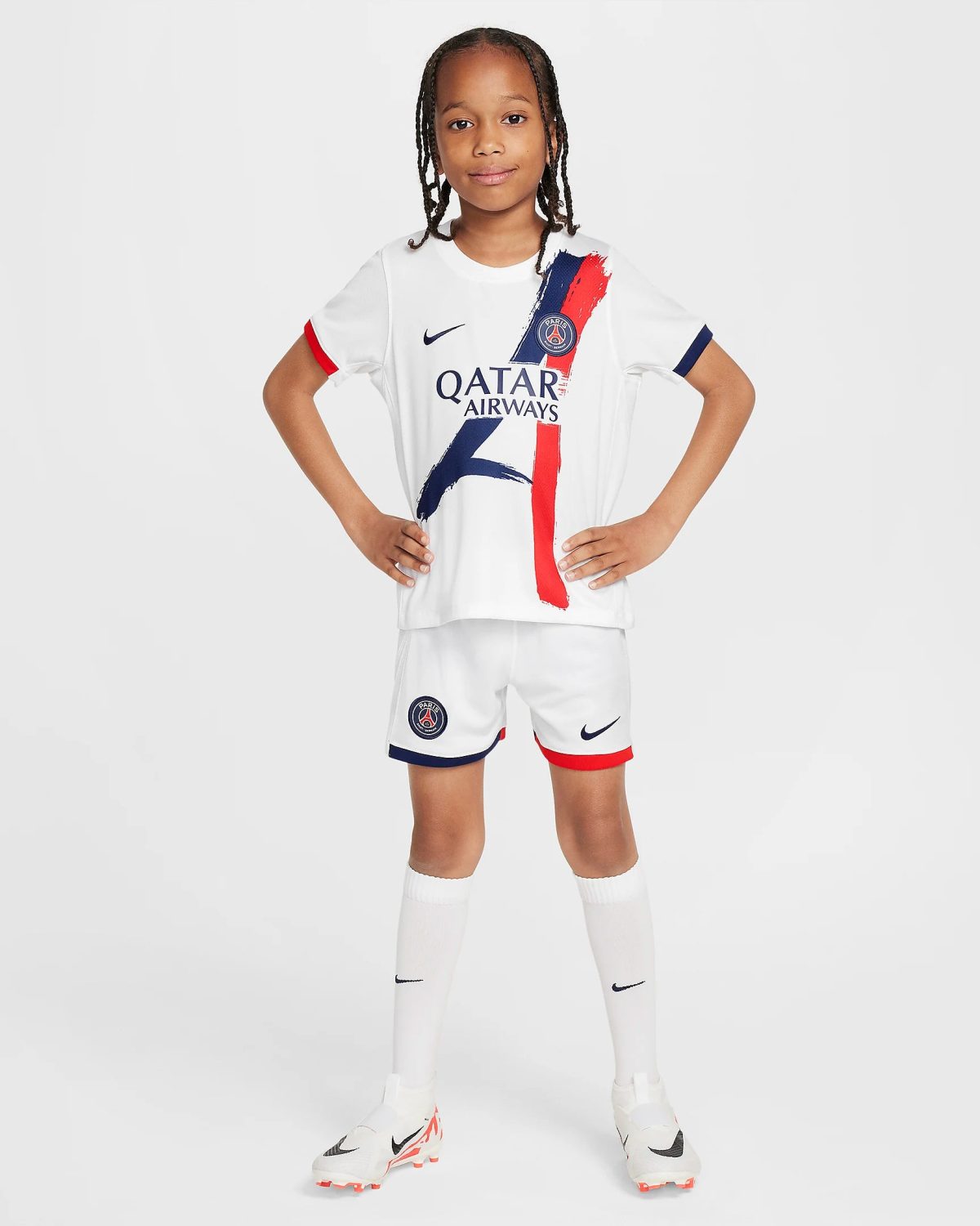 Girl wearing a white Paris Saint-Germain soccer kit with Qatar Airways sponsor, standing with hands on hips.