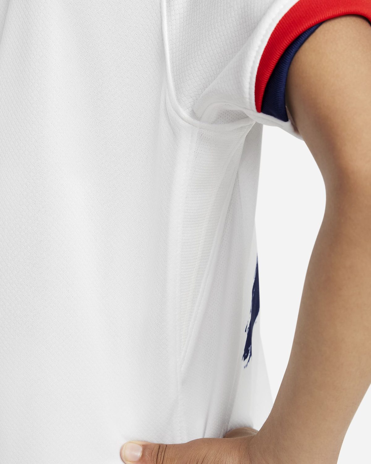 Close-up of a white garment sleeve with red and blue trim, an arm resting beside it.