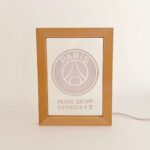 Paris-Saint-Germain-Wooden-Frame-Light-scaled-1 | UAE SPORT STORE Wooden frame displaying a PSG logo and text Paris Saint‑Germain football club on a white surface.