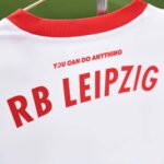 White jersey with red collar and bold red text reading 'RB LEIPZIG' on the back.