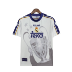 White Real Madrid jersey on a wooden hanger with purple collar, yellow trim, crest, and a large grayscale graphic of a player.