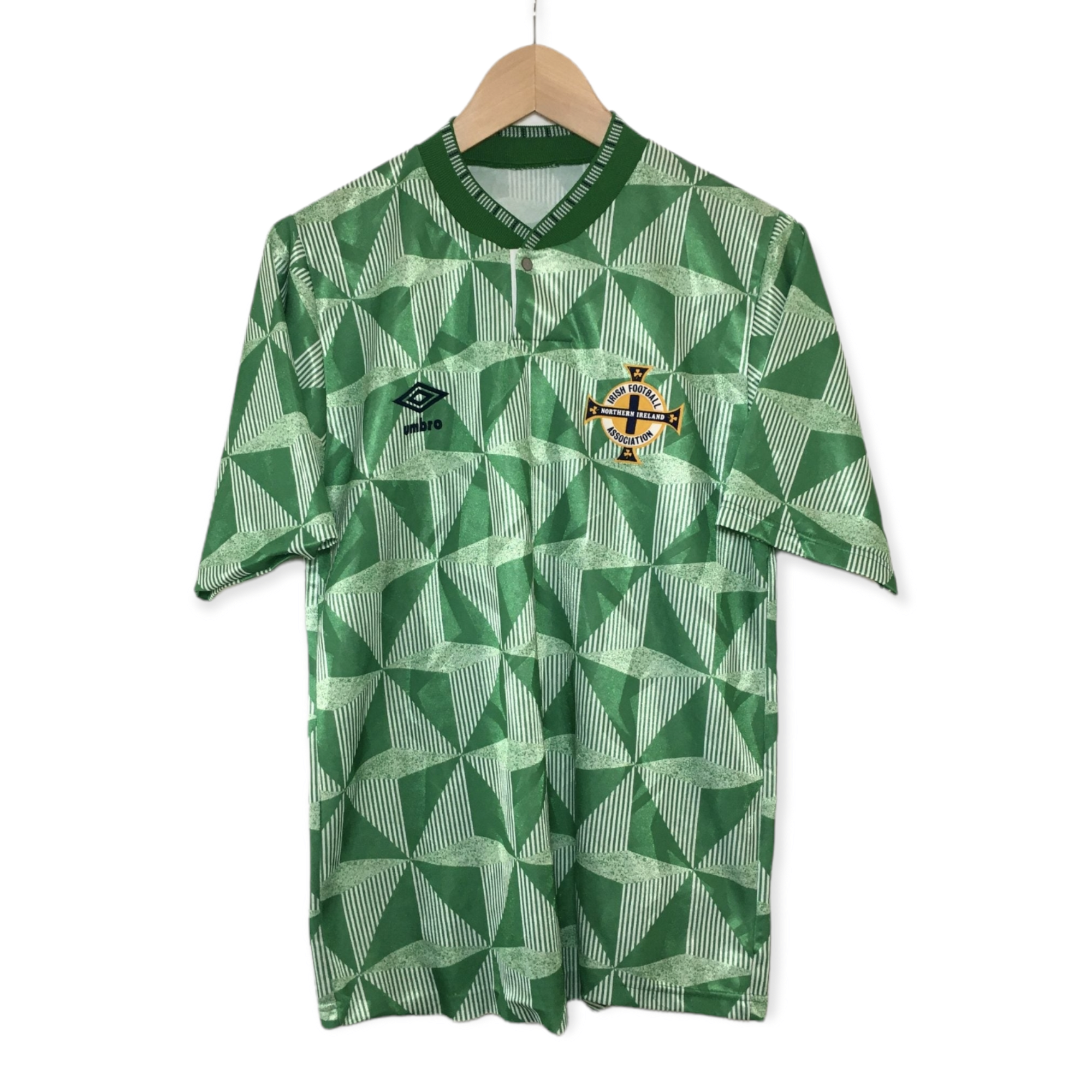 PhotoRoom-20220411_234300_fdf04093-77c5-4f2e-8f02-351dde2cc52f | UAE SPORT STORE Green geometric football jersey hanging on a wooden hanger, featuring the Northern Ireland Football Association crest and Umbro logo on the chest.