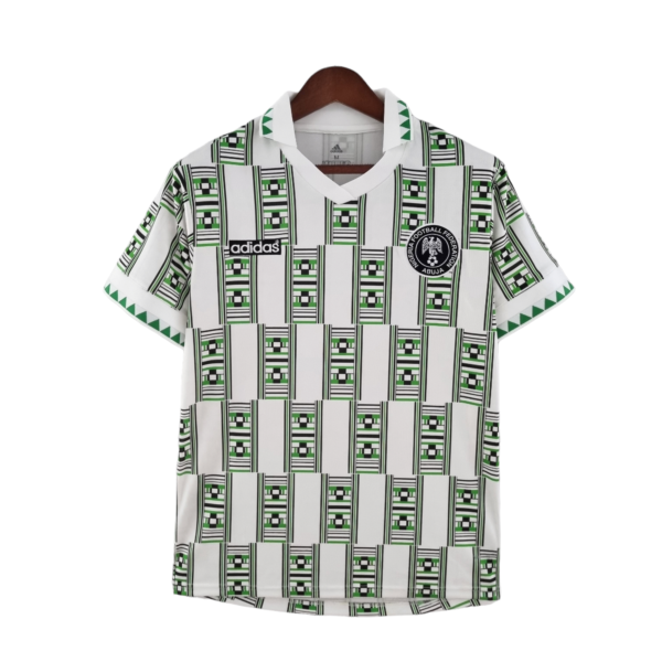 White football jersey on a hanger with green/black geometric patterns, Adidas logo, and Nigeria Football Federation crest.