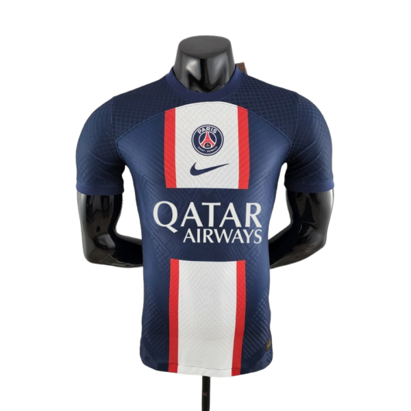 Front view of a Paris Saint-Germain football jersey on a mannequin: navy blue with white and red central panel, Nike swoosh, PSG crest, and Qatar Airways sponsor.
